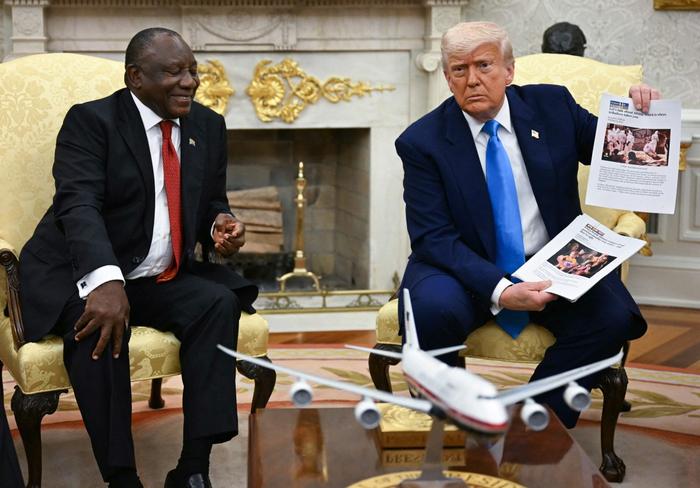 Donald Trump montre des photos à l'occasion de sa rencontre avec le président sud-africain Cyril Ramaphosa dans le bureau ovale de la Maison Blanche à Washington, le 21 mai 2025.