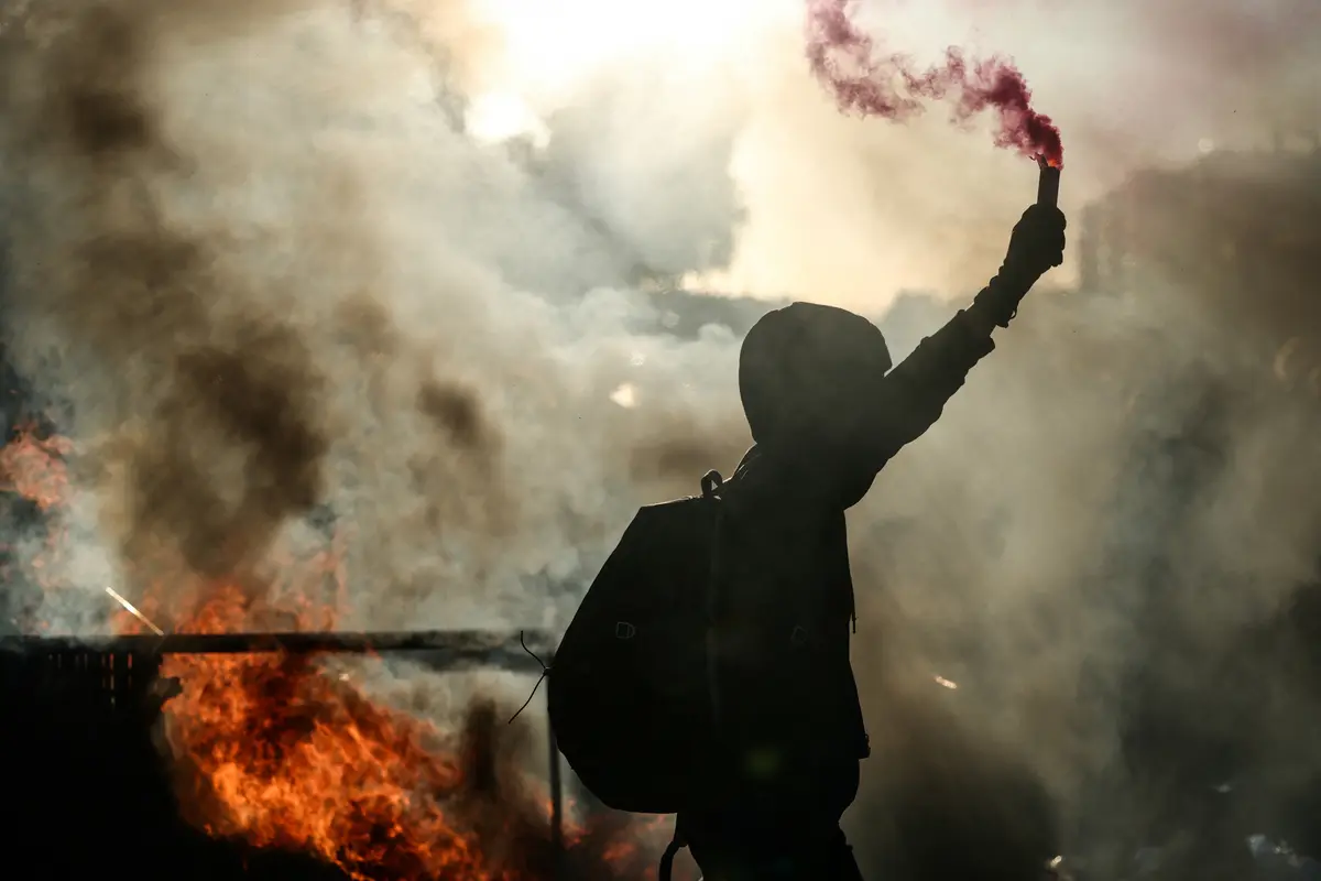 Un manifestant brandit un fumigène près d'une barricade en feu lors d'une manifestation du mouvement « Bloquons tout », dans le sud-est de Paris, le 10 septembre 2025. (Photo by Alain JOCARD / AFP)