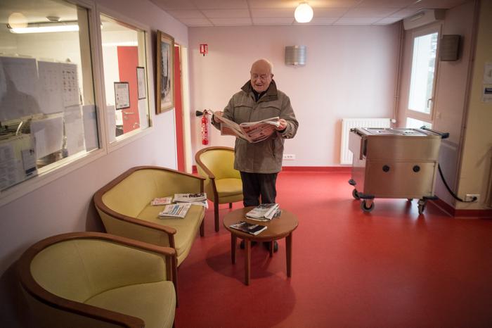 Un résident lit un journal dans un couloir le 4 mars 2020, dans un EHPAD de Brest, en pleine période de pandémie du COVID-19.
