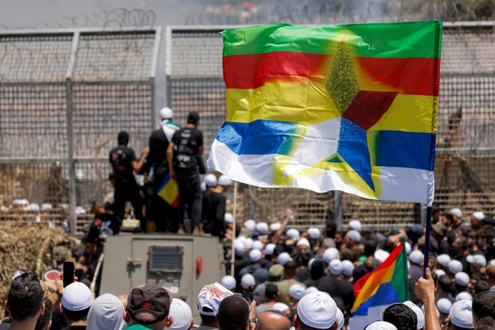 Des membres de la communauté druze manifestent devant les forces israéliennes près de la clôture de barbelés séparant le plateau du Golan annexé par Israël de la Syrie, près de Majdal Shams, le 16 juillet 2025.