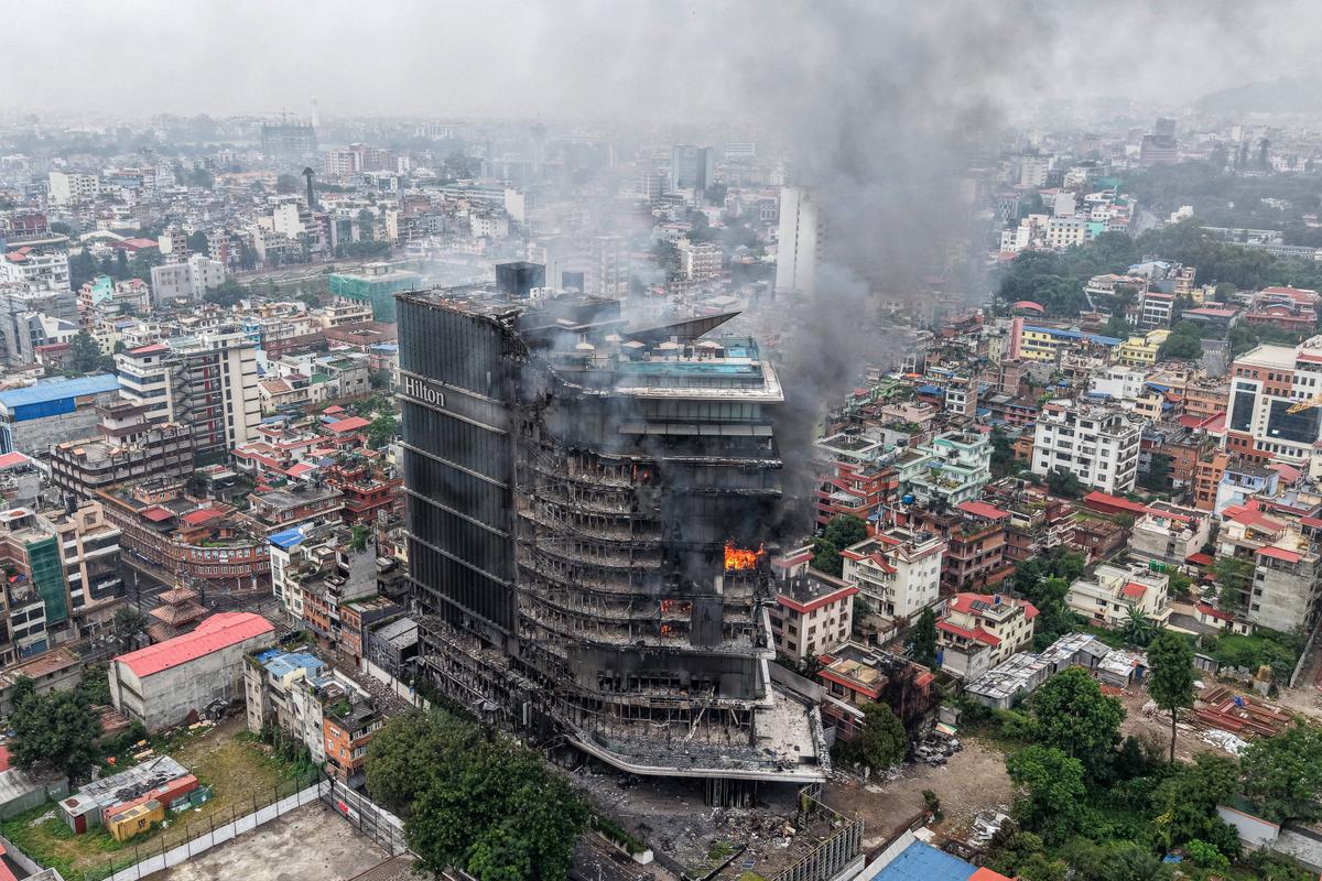 De la fumée s'échappe des hôtels Hilton en feu, un jour après qu'ils ont été incendiés par des manifestants à Katmandou le 10 septembre 2025. (Photo by PRABIN RANABHAT / AFP)