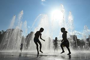 Des enfants se rafraîchissent dans une fontaine à Colmar, dans l'est de la France, le 13 août 2021. 