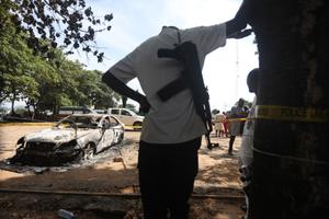 Un policier se tient près d'un véhicule pénitentiaire incendié à Abuja, au Nigeria, le 6 juillet 2022, après l'attaque de la prison moyenne de Kuje par des hommes armés présumés de Boko Haram.