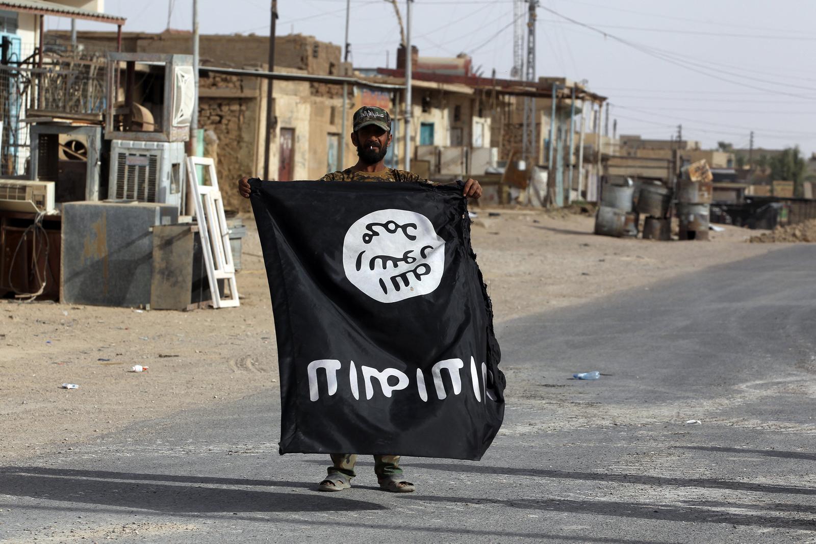 Un membre irakien des Hachd al-Chaabi (Unités de mobilisation populaire) porte un drapeau du groupe État islamique dans la ville d'al-Qaim, dans l'ouest de l'Irak, le 3 novembre 2017. Image d'illustration