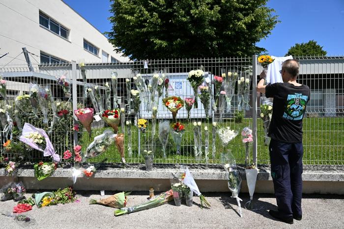 Un homme accroche des fleurs à la clôture du collège Françoise Dolto à Nogent, le 11 juin 2025, au lendemain de l'arrestation d'un lycéen qui a tué au couteau une assistante scolaire de 31 ans lors d'une fouille de sac.