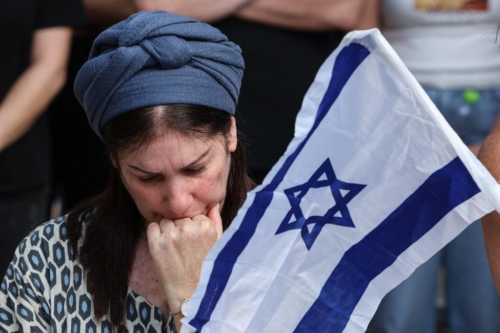 Une femme réagit près d'un drapeau israélien lors des funérailles d'Oz Daniel — un caporal israélien de 19 ans tué par des militants palestiniens lors des attaques du 7 octobre 2023 — dans un cimetière militaire de Kfar Saba, le 6 novembre 2025.
