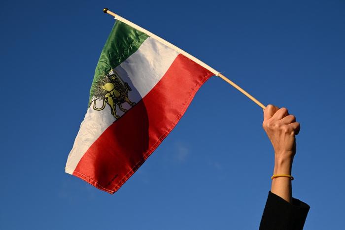 Un manifestant brandit un drapeau iranien d'avant la révolution islamique de 1979 lors d'une manifestation contre la répression des manifestations par le régime iranien dans le centre de Paris, le 4 janvier 2026.