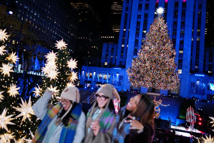 Des personnes dansent devant le sapin de Noël illuminé, quelques instants après son illumination lors de l'événement d'illumination du sapin de Noël du Rockefeller Center à New York, le 3 décembre 2025.