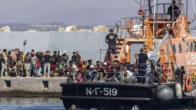 Des migrants secourus en mer au large de l'île grecque de Crète débarquent d'un navire de sauvetage des garde-côtes grecs dans le port d'Agia Galini avant d'être transférés le 6 juillet 2025.
