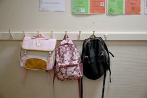 Des sacs à dos sont accrochés à un porte-manteau dans un couloir d'une école primaire à Paris, le 1er septembre 2025.
