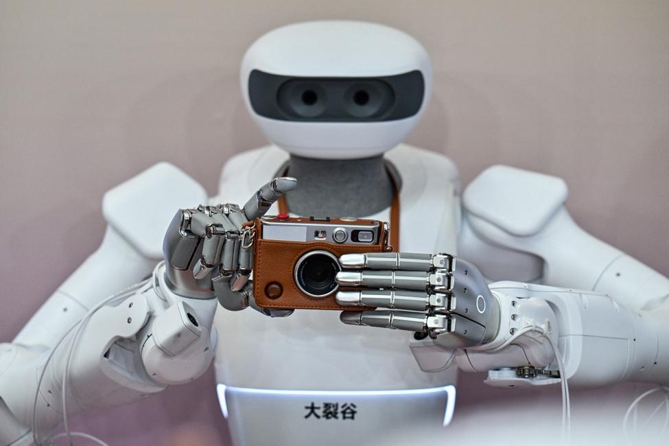 Un robot humanoïde s'apprête à prendre une photo avec un appareil Instax lors de la Conférence mondiale sur l'intelligence artificielle (WAIC) à Shanghai, le 18 juillet 2026.