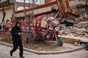 Un homme passe devant un bâtiment effondré après un tremblement de terre à Dahejia, dans le comté de Jishishan, province du Gansu (nord-ouest de la Chine), le 19 décembre 2023.