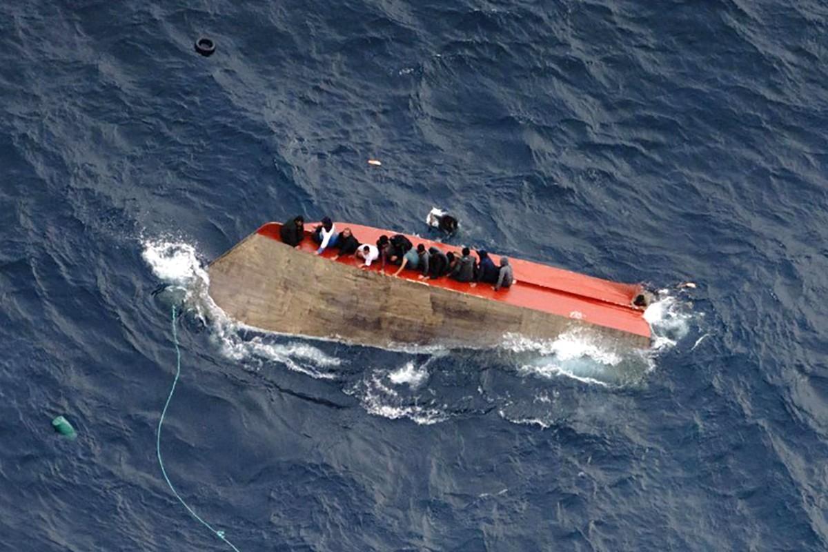 Des migrants assis sur une embarcation chavirée au large de la Libye.