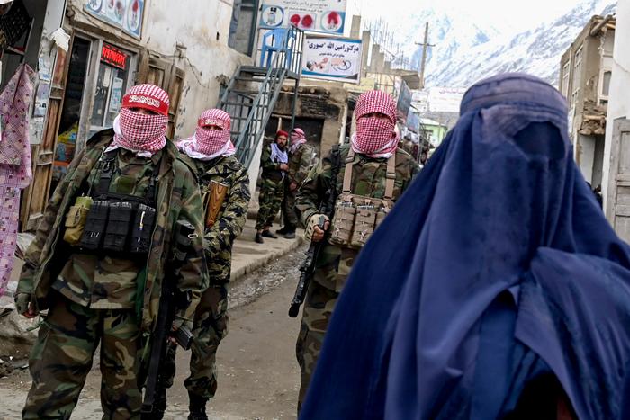 Des agents de sécurité talibans montent la garde tandis qu'une femme afghane vêtue d'une burqa marche dans la rue d'un marché du district de Baharak, dans la province du Badakhshan, le 26 février 2024. (Image d'illustration)