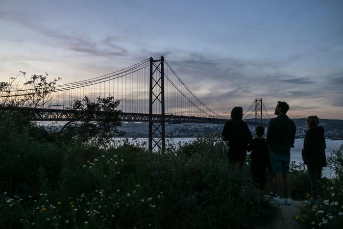 Une famille regarde le pont du 25 avril, à Lisbonne, avec les lumières éteintes lors d'une panne de courant massive affectant toute la péninsule ibérique, 28 avril 2025.