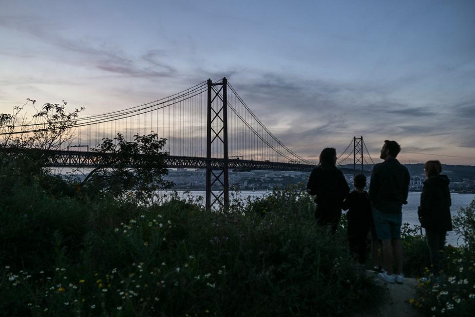 Une famille regarde le pont du 25 avril, à Lisbonne, avec les lumières éteintes lors d'une panne de courant massive affectant toute la péninsule ibérique, 28 avril 2025.