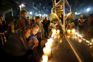 Une mère allume une bougie avec son enfant, devant l'ambassade de France à Séoul, le 14 novembre.