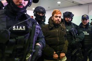 Le trafiquant de drogue français condamné Mohamed Amra est escorté par des policiers à l'aéroport international Henri Coanda d'Otopeni, près de Bucarest, en Roumanie, le 25 février 2025.