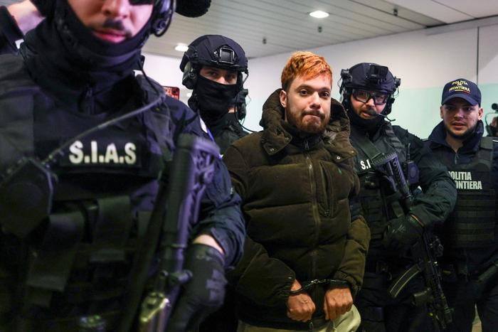 Le trafiquant de drogue français condamné Mohamed Amra est escorté par des policiers à l'aéroport international Henri Coanda d'Otopeni, près de Bucarest, en Roumanie, le 25 février 2025.