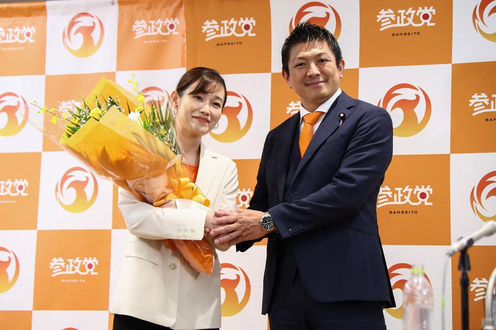 Le chef du parti Sanseito du Japon, Sohei Kamiya serre la main d'une candidate à Tokyo, le 20 juillet 2025.