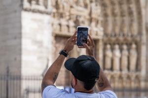 Un touriste prend une photo de la cathédrale Notre-Dame de Paris avec son smartphone, dans le centre de Paris, le 15 juillet 2026. 
