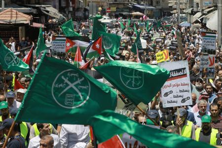 Des drapeaux des Frères musulmans, de la Jordanie et d'autres partis politiques sont brandis parmi d'autres pancartes de protestation dénonçant la conférence économique du Moyen-Orient menée par les États-Unis à Bahreïn, lors d'une manifestation organisée après la prière du vendredi contre le « Plan du siècle » du président américain Donald Trump à Amman.
