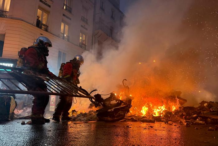 Des pompiers tentent d’éteindre un incendie provoqué par des manifestants bloquant une rue près de la place des Fêtes, à Paris, lors d’une mobilisation du mouvement « Bloquons tout », le 10 septembre 2025. Cette vaste campagne antigouvernementale appelait à mettre la France à l’arrêt par une série d’actions de protestation et de désobéissance civile, alors que la passation de pouvoir entre le nouveau Premier ministre et son prédécesseur, défait lors du vote de confiance du 8 septembre, devait avoir lieu le même jour à midi.