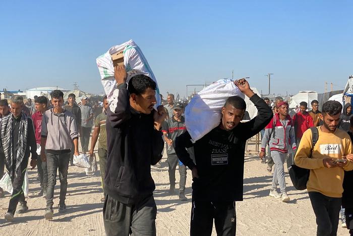 Des Palestiniens transportant des sacs de fournitures de secours à Rafah, le 29 mai 2025.