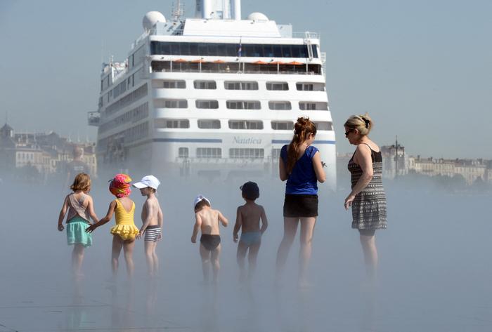 Des femmes et des enfants se rafraîchissent dans le Miroir d'eau, profitant du soleil, à Bordeaux, dans l'ouest de la France.