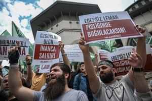 Des manifestants brandissent des pancartes, dont l’une où l’on peut lire « LeMan immoral, tu te noieras dans ta saleté » (à droite), pour protester contre les dessinateurs d’un magazine satirique accusé d’avoir publié une caricature du prophète Mahomet, devant la mosquée Taksim à Istanbul, le 1ᵉʳ juillet 2025.