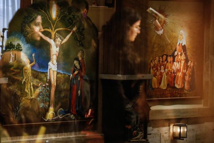 Des peintures religieuses apparaissent derrière le reflet des fidèles assistant à la messe du Vendredi saint à l'église catholique chaldéenne Notre-Dame du Perpétuel Secours à Erbil, capitale de la région kurde autonome du nord de l'Irak, le 3 avril 2026.