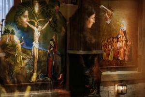 Des peintures religieuses apparaissent derrière le reflet des fidèles assistant à la messe du Vendredi saint à l'église catholique chaldéenne Notre-Dame du Perpétuel Secours à Erbil, capitale de la région kurde autonome du nord de l'Irak, le 3 avril 2026.