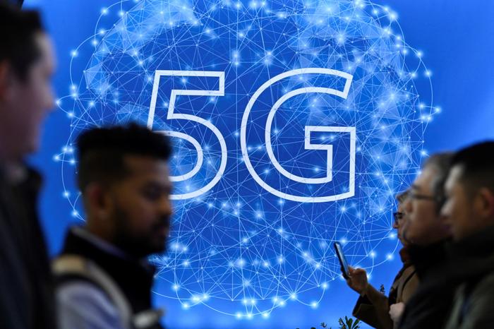 Des visiteurs passent devant un panneau 5G lors du Mobile World Congress (MWC), le plus grand rassemblement annuel de l'industrie des télécommunications, à Barcelone, le 28 février 2023.