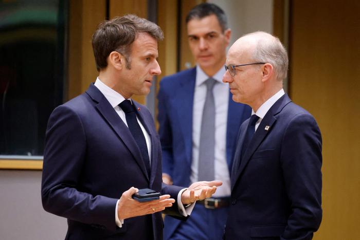 Emmanuel Macron et le Premier ministre luxembourgeois Luc Frieden discutent pendant que le Premier ministre espagnol Pedro Sanchez passe devant eux lors d'une séance de travail du Conseil européen lors d'un sommet de l'Union européenne à Bruxelles le 20 mars 2025.