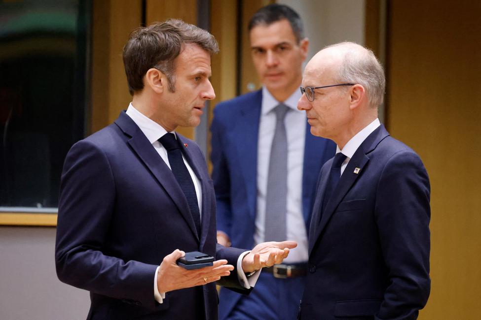 Emmanuel Macron et le Premier ministre luxembourgeois Luc Frieden discutent pendant que le Premier ministre espagnol Pedro Sanchez passe devant eux lors d'une séance de travail du Conseil européen lors d'un sommet de l'Union européenne à Bruxelles le 20 mars 2025.
