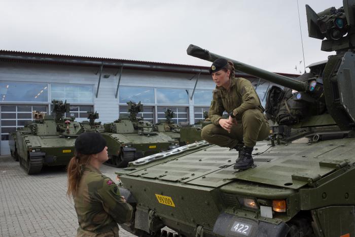 Des femmes soldats discutent à côté d'un véhicule de combat CV90 au bataillon blindé de Setermoen, dans le nord de la Norvège, le 11 août 2016.