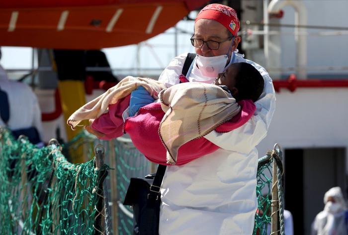 Un médecin porte un enfant alors que des migrants débarquent navires de Médecins Sans Frontières (MSF) dans le port de Pozzallo en Italie , le 25 Avril 2016.