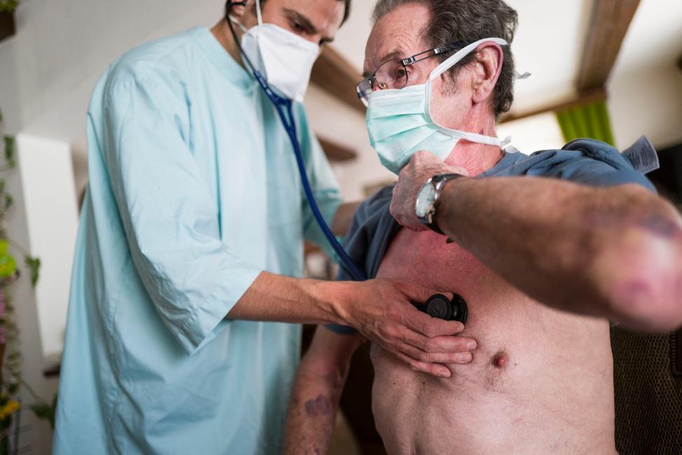 Un docteur examine le rythme cardiaque d'un patient fraîchement sorti de l'hôpital après avoir été infecté par la COVID-19, lors d'une consultation à domicile, dans l'est de la France.