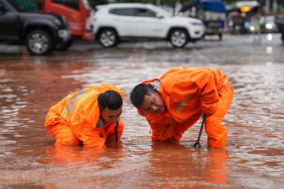 Des ouvriers draguent un égout dans une rue inondée après de fortes pluies à Changsha, dans la province du Hunan, au centre de la Chine, le 24 juin 2024.