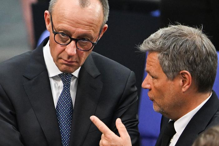 Le ministre allemand de l'Économie et de la Protection du climat et principal candidat des Verts, Robert Habeck s'entretient avec Friedrich Merz, chef de l'Union chrétienne-démocrate (CDU), lors de la séance constitutive du nouveau Bundestag, le 25 mars 2025 à Berlin.