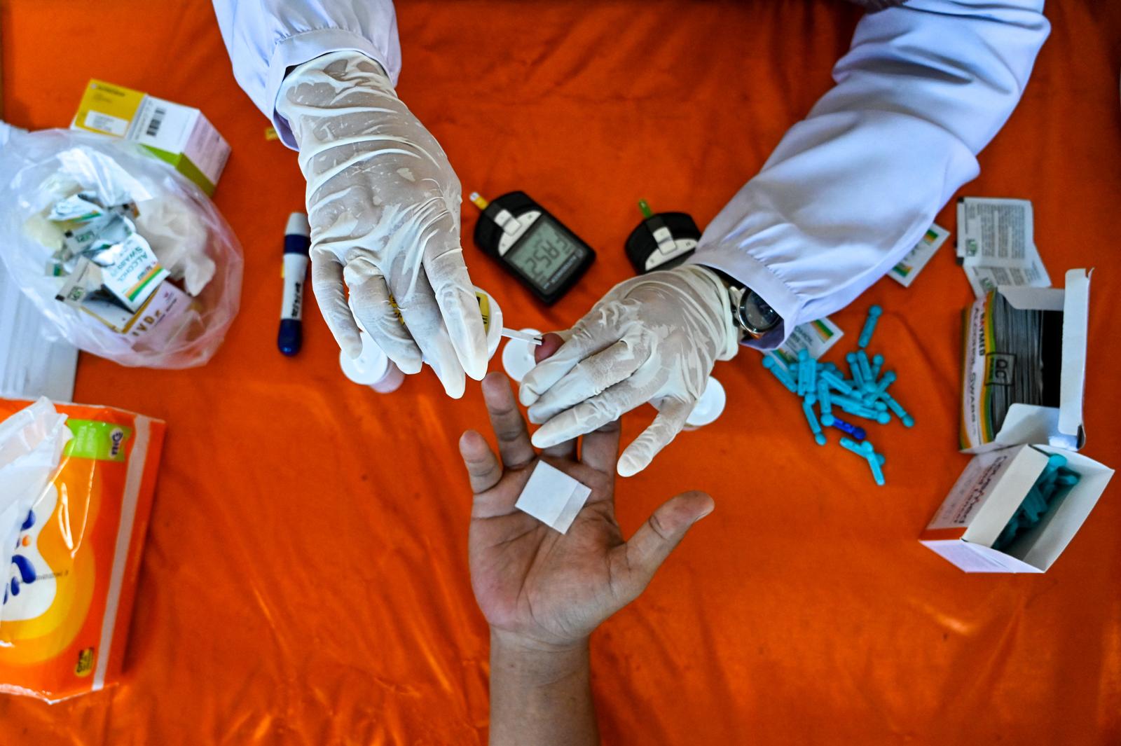 Un homme se fait prélever un échantillon de sang lors d'un examen médical pour hypertension, cholestérol et diabète dans un poste de services intégrés à Banda Aceh, le 11 février 2025.
