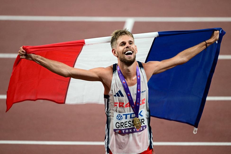L'athlète français Jimmy Gressier, premier au classement, célèbre avec le drapeau de son pays et sa médaille après avoir remporté la finale du 10 000 m masculin lors des Championnats du monde d'athlétisme à Tokyo le 14 septembre 2025. (Photo de Yuichi YAMAZAKI / AFP)
