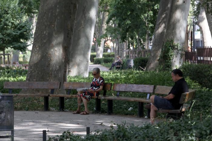 Un homme et une femme se reposent à l'ombre des arbres pour se rafraîchir dans un parc de Perpignan, dans le sud de la France.