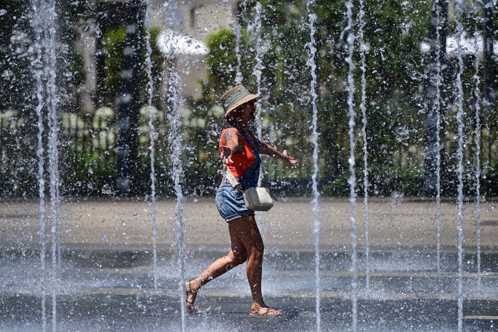 Une femme traverse une fontaine pour se rafraîchir alors qu'une vague de chaleur frappe le sud de l'Europe, à Béziers, dans le sud de la France, le 28 juin 2025.