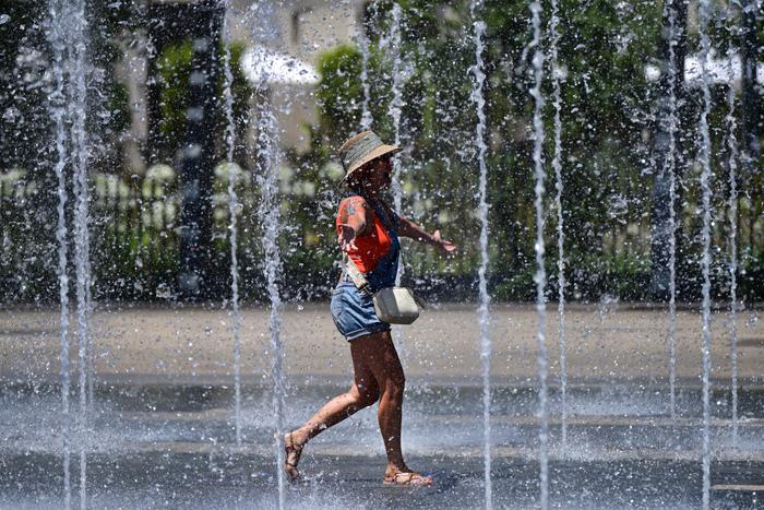 Une femme traverse une fontaine pour se rafraîchir alors qu'une vague de chaleur frappe le sud de l'Europe, à Béziers, dans le sud de la France, le 28 juin 2025.
