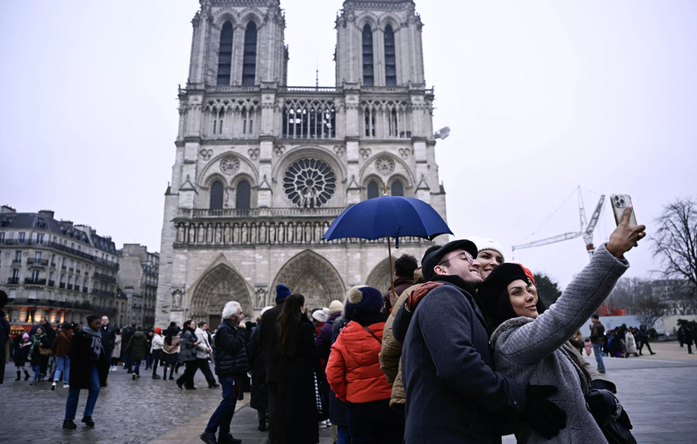 Des touristes qui profitent du bonheur de redécouvrir la cathédrale Notre-Dame de Paris après sa réouverture.