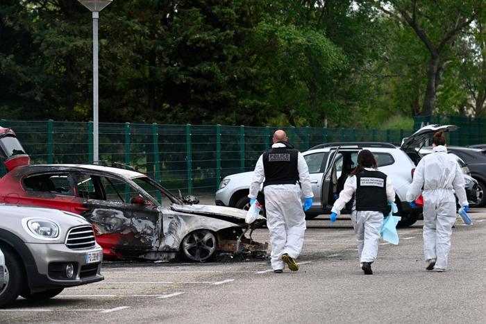 Des policiers de la police scientifique arrivent à proximité d'une voiture incendiée devant la maison d'arrêt de Tarascon, le 16 avril 2025, après que 3 voitures ont été incendiées la nuit précédente sur son parking.