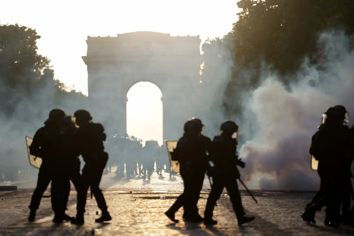 Des CRS marchent au milieu de la fumée des gaz lacrymogènes sur l'avenue des champs-Élysées, après le match de football entre le Paris Saint-Germain (PSG) et l'Arsenal FC joué à Budapest, le 30 mai 2026.