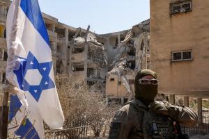 Un policier israélien masqué monte la garde devant un bâtiment qui a été touché par un missile iranien à Holon, ville centrale d'Israël, le 19 juin 2025.