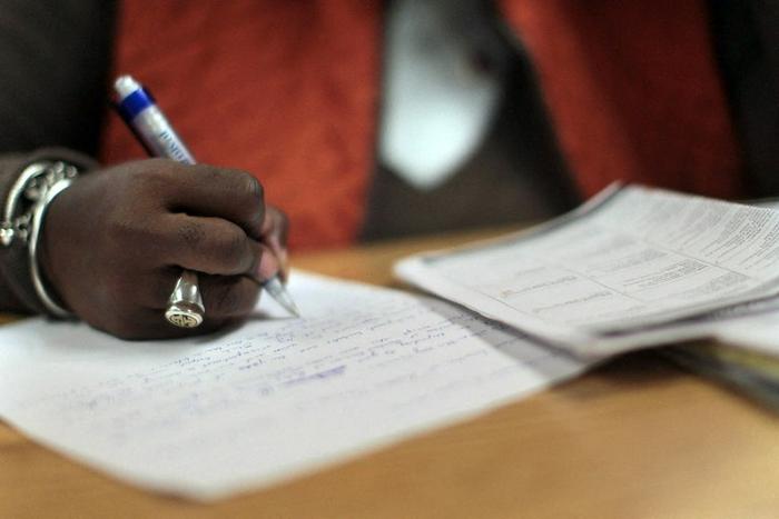 Une femme rédige une lettre de motivation manuscrite dans un centre de formation professionnelle géré par le Département du Travail de l'État de New York.